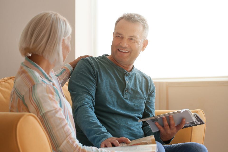 An older couple on the sofa going through their reading together, smiling