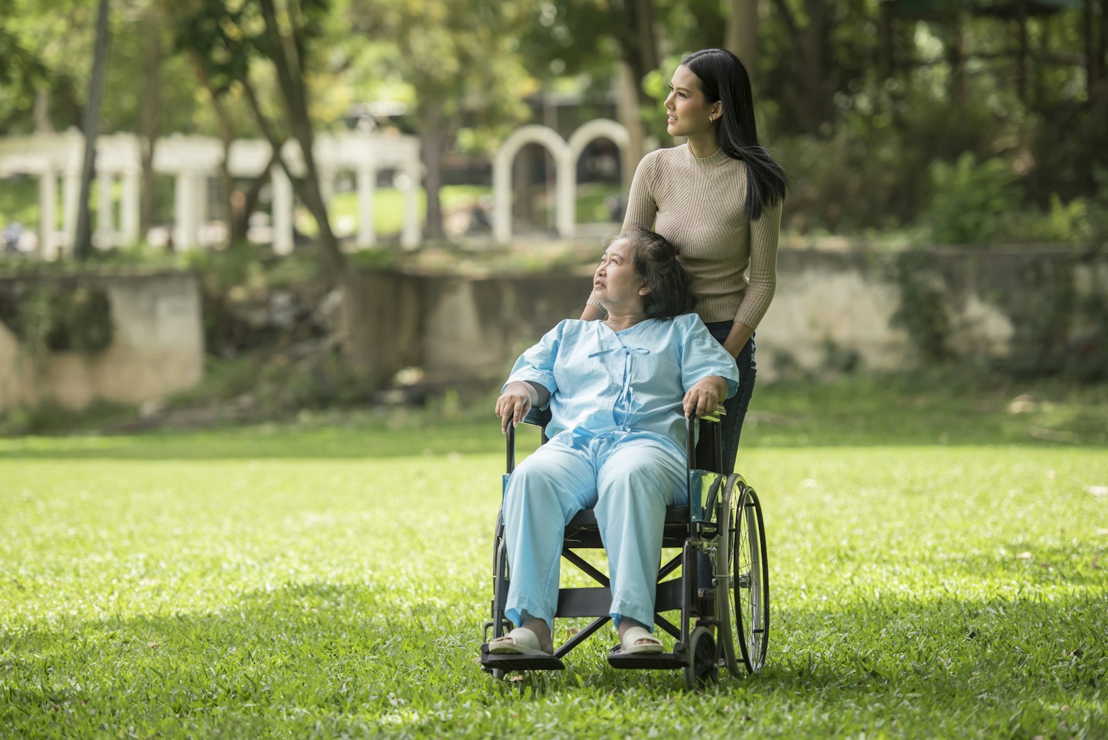 A young woman taking an older woman in a wheelchair out to the park