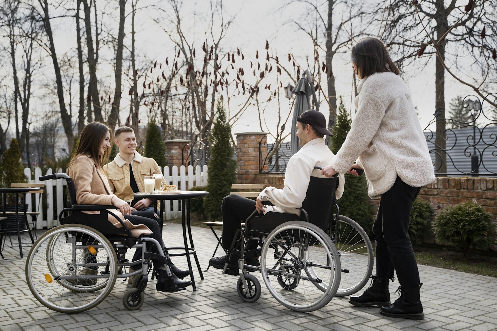 Friends, two using wheelchairs, sharing a coffee at an outdoor café