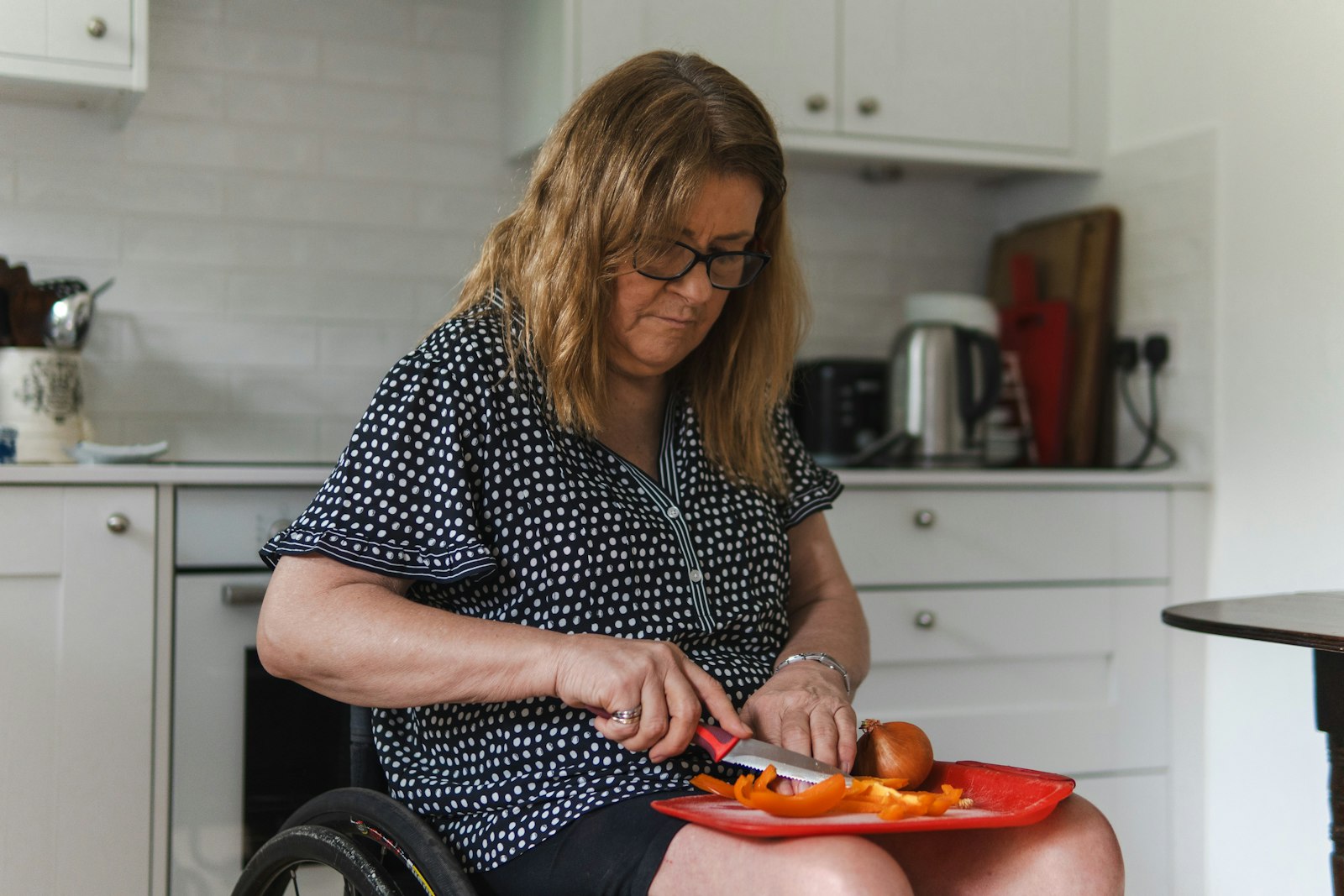 A woman in a wheelchair preparing food in her kitchen