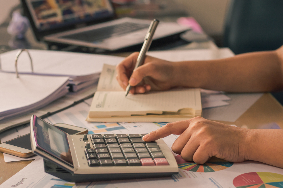 Hands working through invoices and receipts with a calculator and a pen