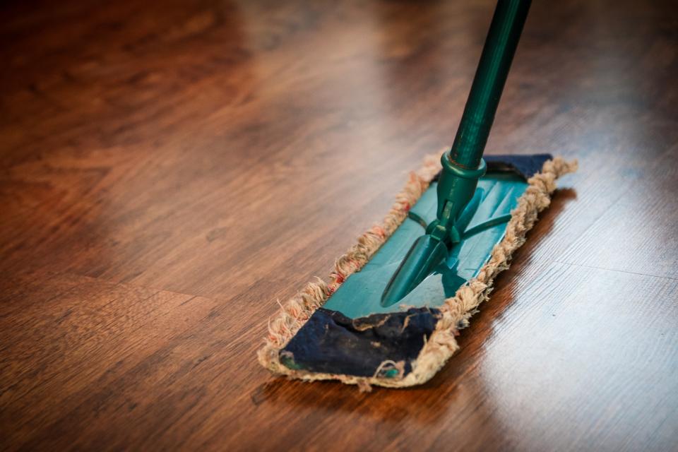 A flat mop cleaning a polished wooden floor at home